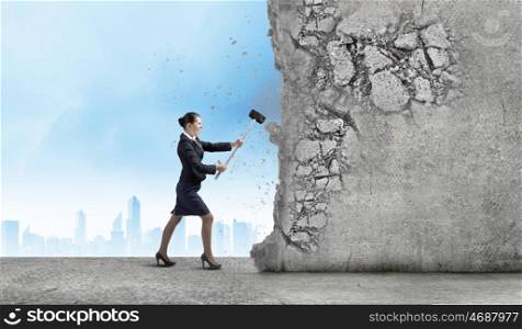 Overcoming challenges. Young attractive businesswoman with hammer in hands