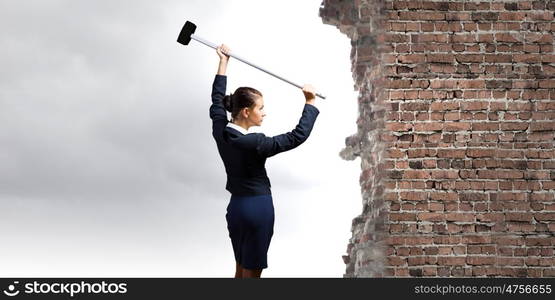 Overcoming challenges. Young attractive businesswoman with hammer in hands