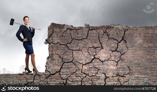 Overcoming challenges. Young attractive businesswoman with hammer in hands