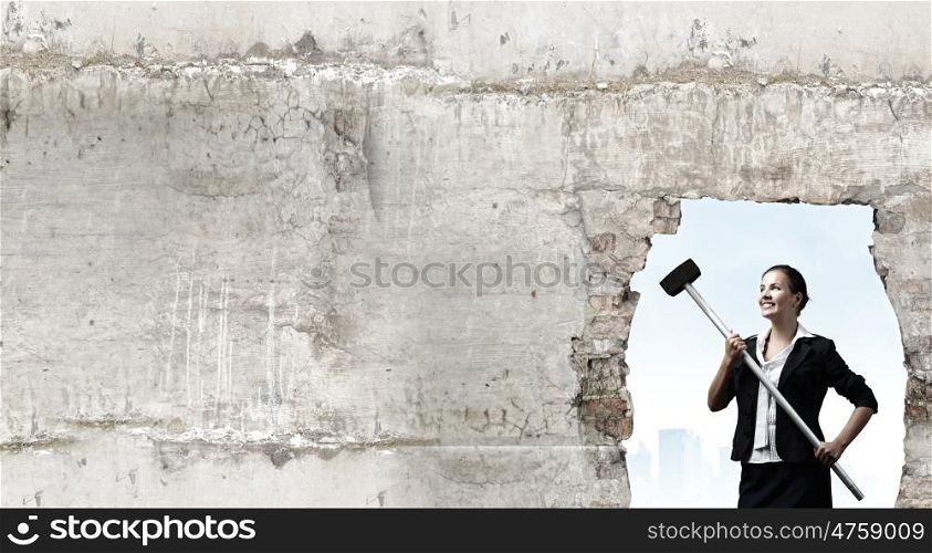 Overcoming challenges. Young attractive businesswoman with hammer in hands