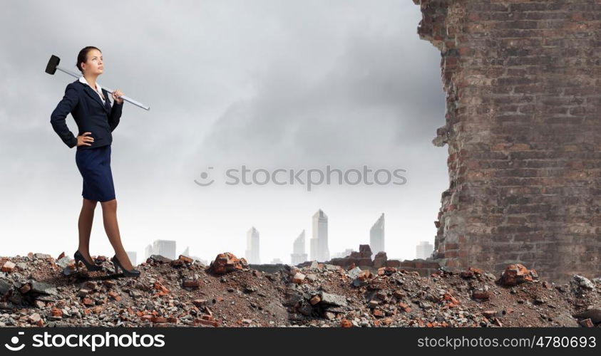 Overcoming challenges. Young attractive businesswoman with hammer in hands