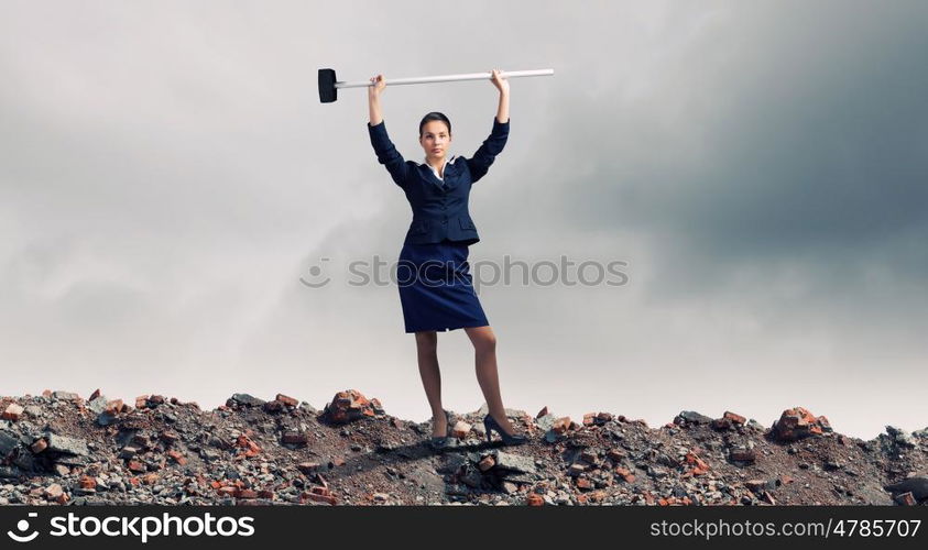 Overcoming challenges. Young attractive businesswoman with hammer in hands