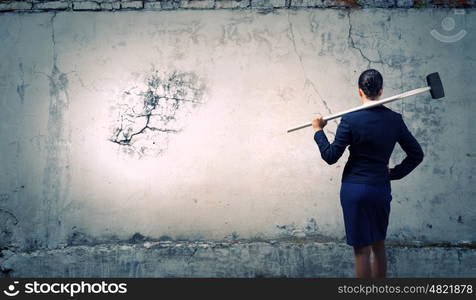 Overcoming challenges. Young attractive businesswoman with hammer in hands