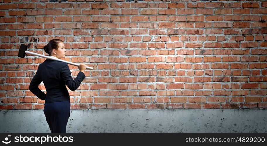 Overcoming challenges. Young attractive businesswoman with hammer in hands