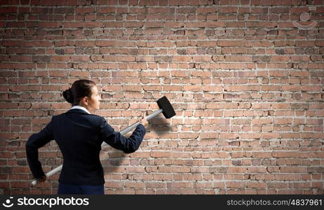 Overcoming challenges. Young attractive businesswoman with hammer in hands