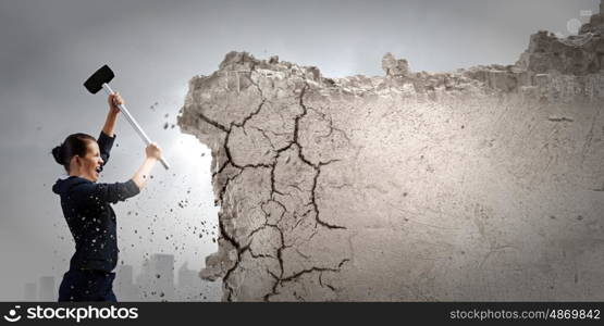 Overcoming challenges. Young attractive businesswoman with hammer in hands