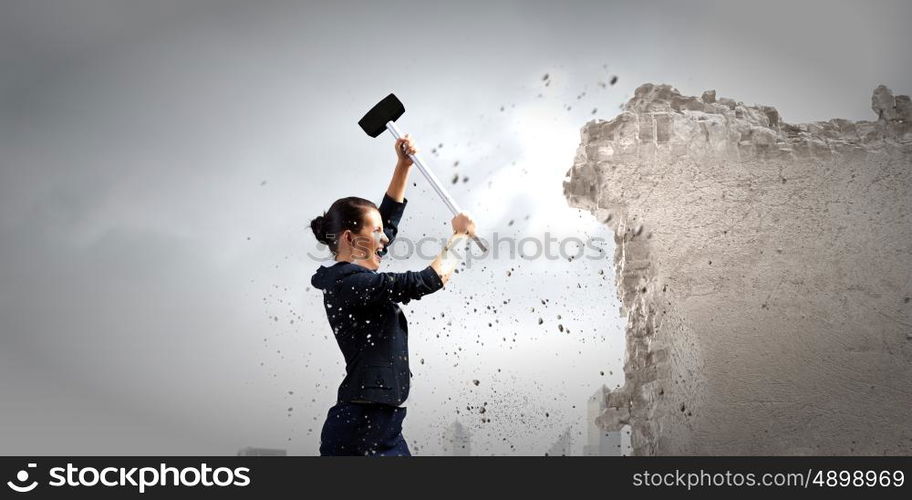 Overcoming challenges. Young attractive businesswoman with hammer in hands