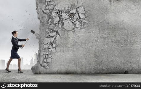 Overcoming challenges. Young attractive businesswoman with hammer in hands