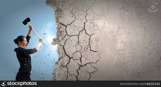 Overcoming challenges. Young attractive businesswoman with hammer in hands