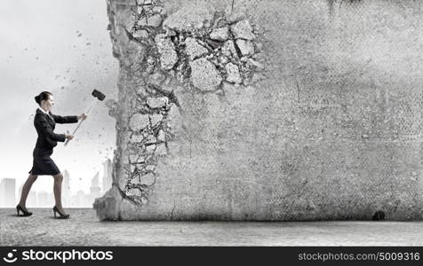 Overcoming challenges. Young attractive businesswoman with hammer in hands