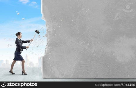 Overcoming challenges. Young attractive businesswoman with hammer in hands