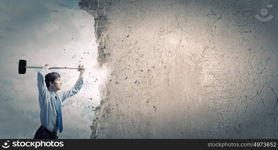 Overcoming challenges. Young determined businessman with hammer in hands