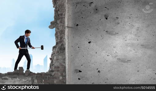 Overcoming challenges. Young determined businessman with hammer in hands