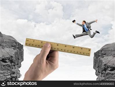 overcoming difficulties. Young successful businessman jumping over gap. Risk and challenge concept