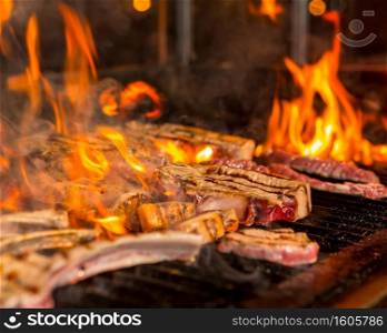Overcooked meat steaks into flames on the grill