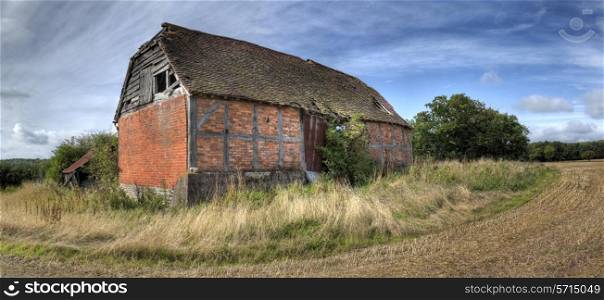 Overgrown timber-frame and brick half-hipped barn, Warwickshire, England.