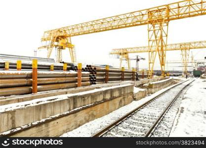 overhead cranes over railroad in metal pipe outdoor warehouse