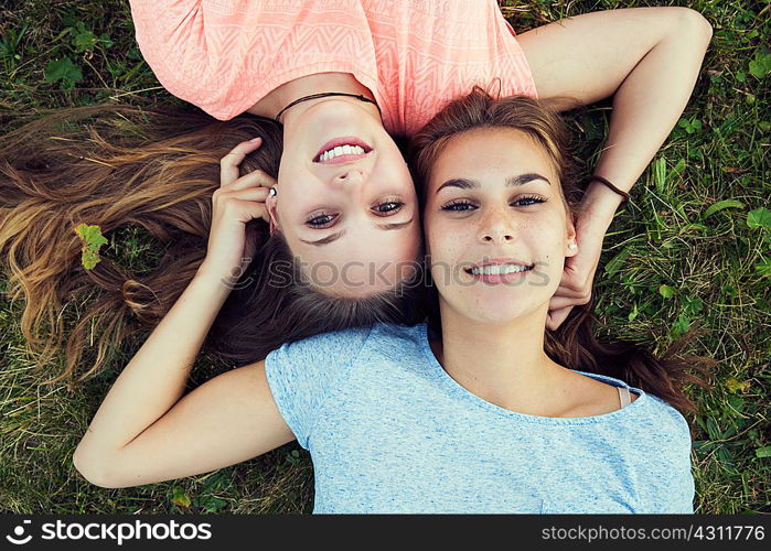Overhead portrait of two young women lying on grass