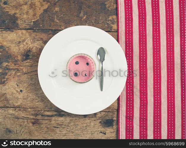 Overhead shot of a cup of yogurt on a plate with a tea towel