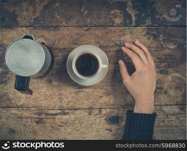 Overhead shot of a male hand with a cup of coffee on a wooden table