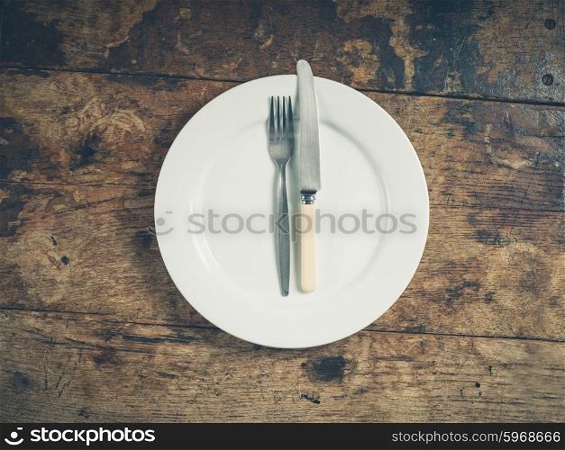 Overhead shot of a white plate with a knife and fork