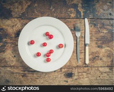 Overhead shot of a white plate with cherry tomatoes on a wooden table