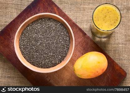 Overhead shot of chia seeds (lat. Salvia hispanica) in clay bowl with mango and mango-chia juice photographed with natural light. Chia seeds are considered a superfood containing proteins, omega fats, minerals and antioxidants
