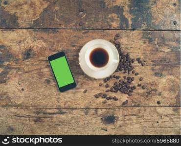 Overhead shot of coffee concept with cup, beans and a smart phone with a green screen
