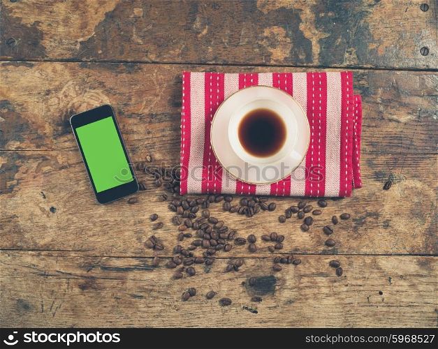 Overhead shot of coffee concept with cup, beans, tea towel and a smart phone with a green screen