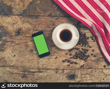 Overhead shot of coffee concept with cup, beans, tea towel and a smart phone with a green screen