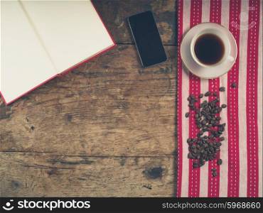 Overhead shot of coffee concept with cup, tea towel, an open book and a smart phone