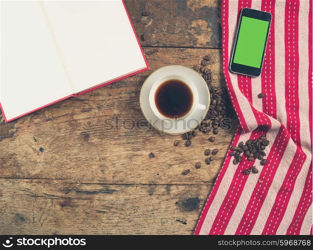Overhead shot of coffee concept with cup, tea towel, an open book and a smart phone with a green screen