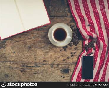 Overhead shot of coffee concept with cup, tea towel, an open book and a smart phone