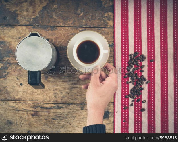 Overhead shot of coffee concept with cup, tea towel and a person&rsquo;s hand