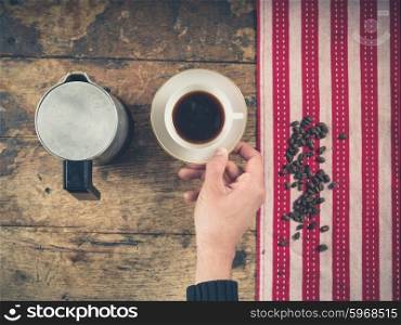 Overhead shot of coffee concept with cup, tea towel and a person&rsquo;s hand