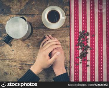 Overhead shot of coffee concept with cup, tea towel and a person&rsquo;s hands