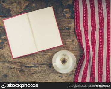 Overhead shot of coffee concept with empty cup, tea towel and an open book with blank pages