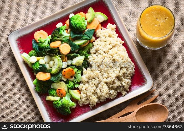 Overhead shot of cooked white quinoa seeds with fried vegetables (carrot, broccoli, spinach, zucchini, corn) and mango juice photographed with natural light