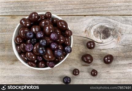 Overhead shot of dark chocolate and blueberries in white bowl on rustic wood