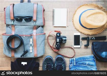 Overhead shot of essentials for traveler. Outfit of young man traveler, camera, mobile device, sunglassses. Travel concept