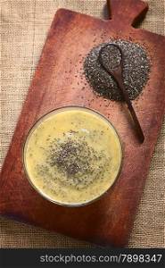 Overhead shot of mango pudding with chia seeds (lat. Salvia hispanica) on wooden board photographed with natural light. Chia seeds are considered a superfood containing proteins, omega fats, minerals and antioxidants. (Selective Focus, Focus on the top of the pudding)