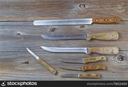 Overhead shot of several vintage knives on rustic wooden boards.