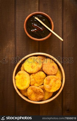 Overhead shot of traditional Chilean Sopaipilla fried pastry made with mashed pumpkin in the dough, served with Chancaca sweet sauce, photographed on wood with natural light