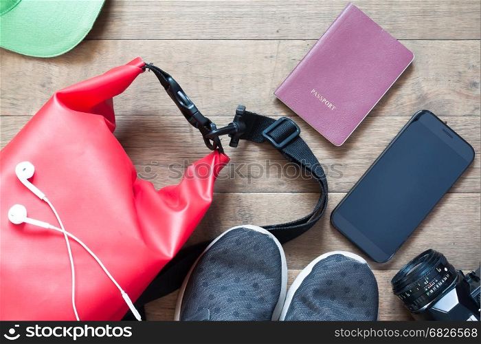 Overhead shot of travel items and accessories with mobile device on wood background, flat lay of summer and vacation items