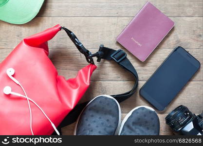 Overhead shot of travel items and accessories with mobile device on wood background, flat lay of summer and vacation items