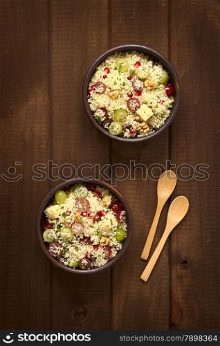Overhead shot of two bowls of vegetarian couscous salad with grapes, pomegranate, walnuts, cheese, lime and mint, photographed with natural light