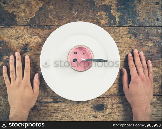 Overhead shot of yogurt on a plate with male hands on either side