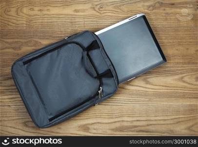 Overhead tilted view of laptop computer and carry case, on rustic wooden boards