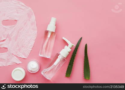 overhead view aloevera spray bottle moisturizer cream pink background