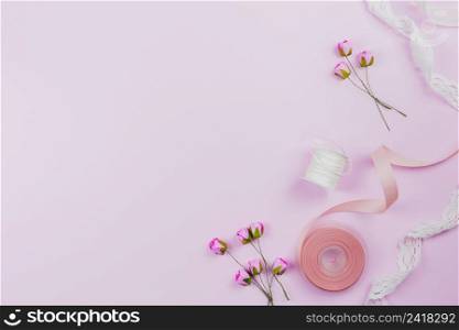 overhead view artificial roses spool ribbons pink background